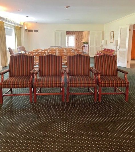 Four upholstered chairs in a room with other seating, a doorway, and a patterned carpet.