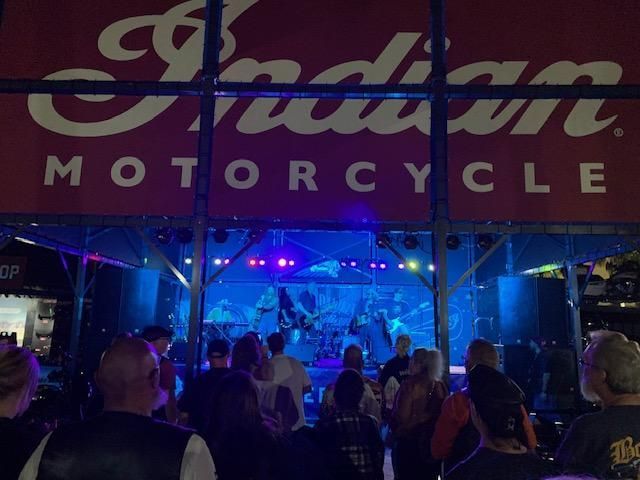 A crowd of people are sitting in front of a stage at a concert.