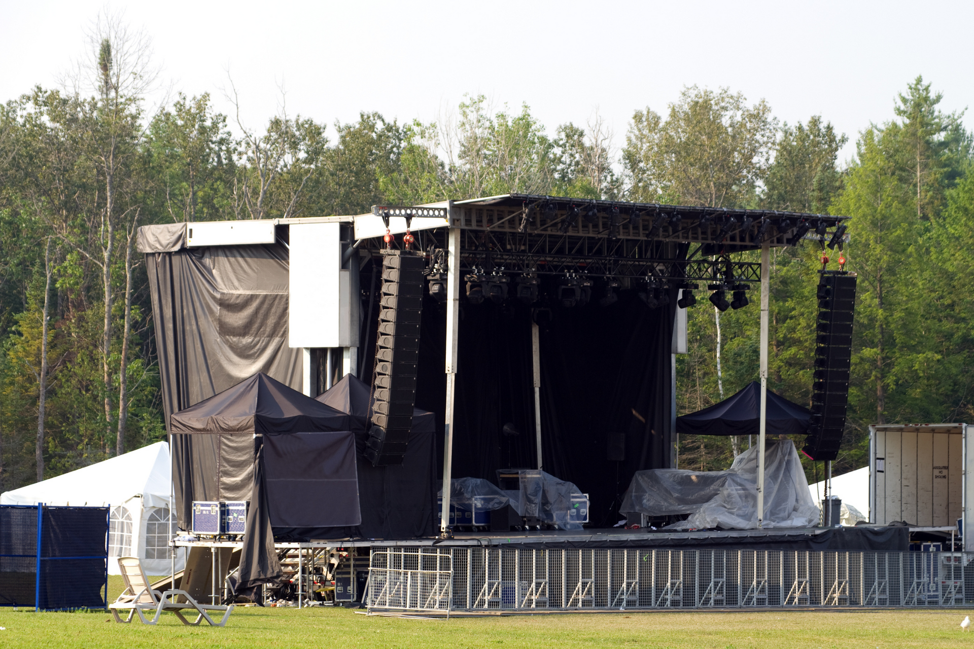 A large stage is being built in a field with trees in the background.