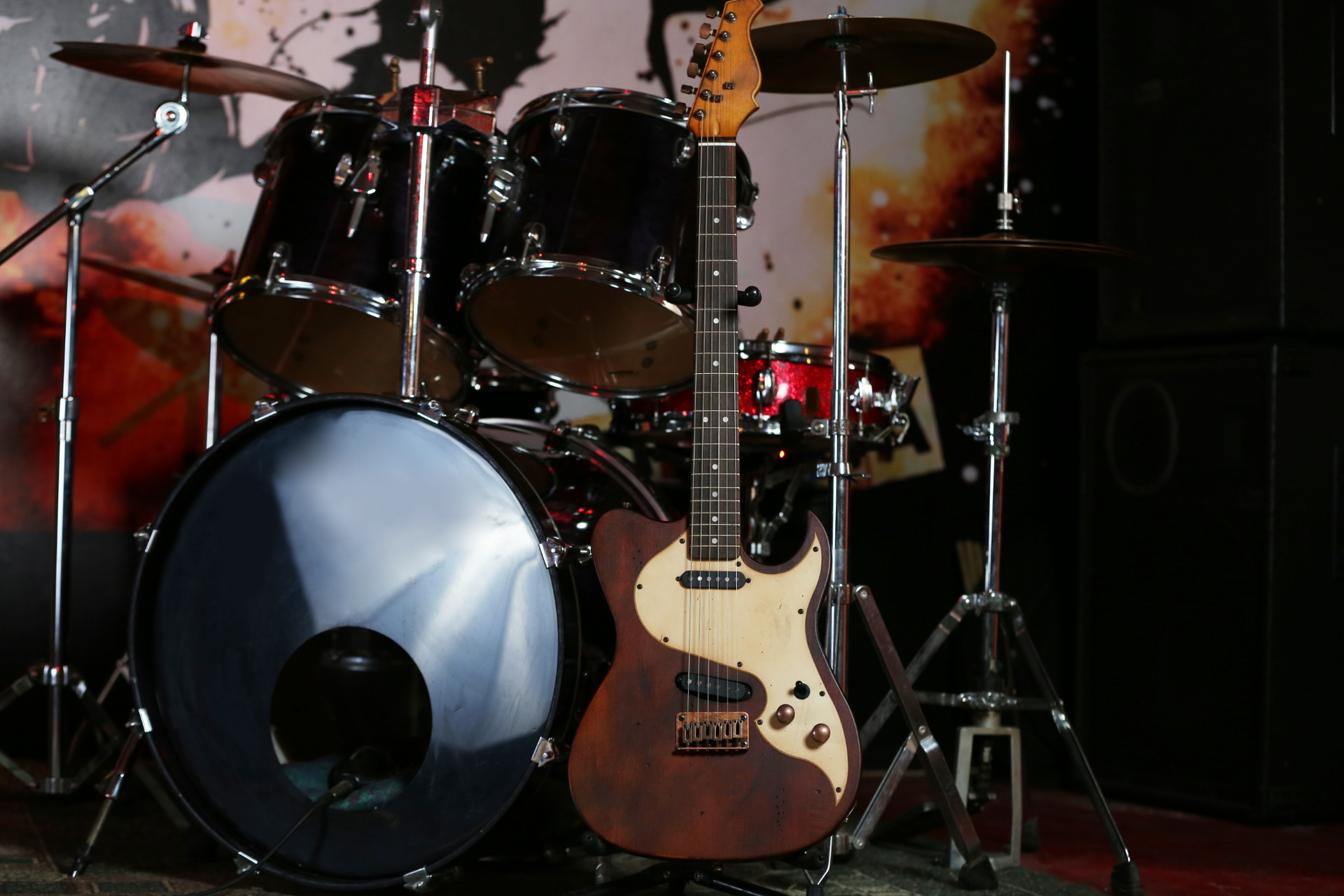 A drum set with a guitar in front of it