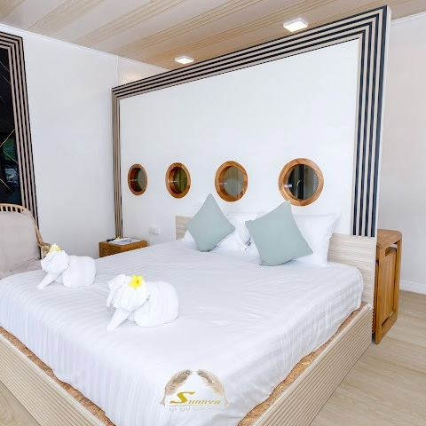 Bedroom with a white bed, round porthole windows, and elephant towel art.