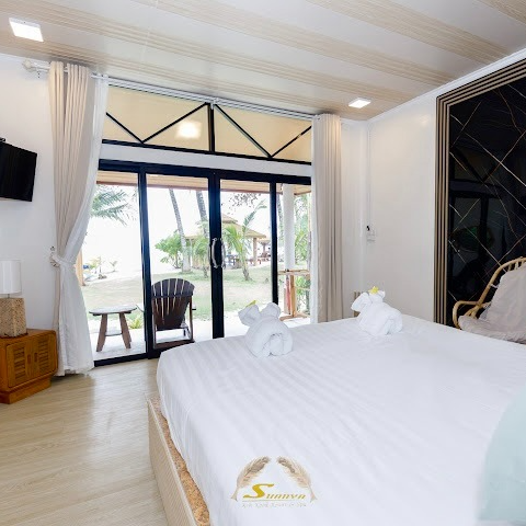 Bedroom with a large bed, sliding glass door, and a view of the beach.