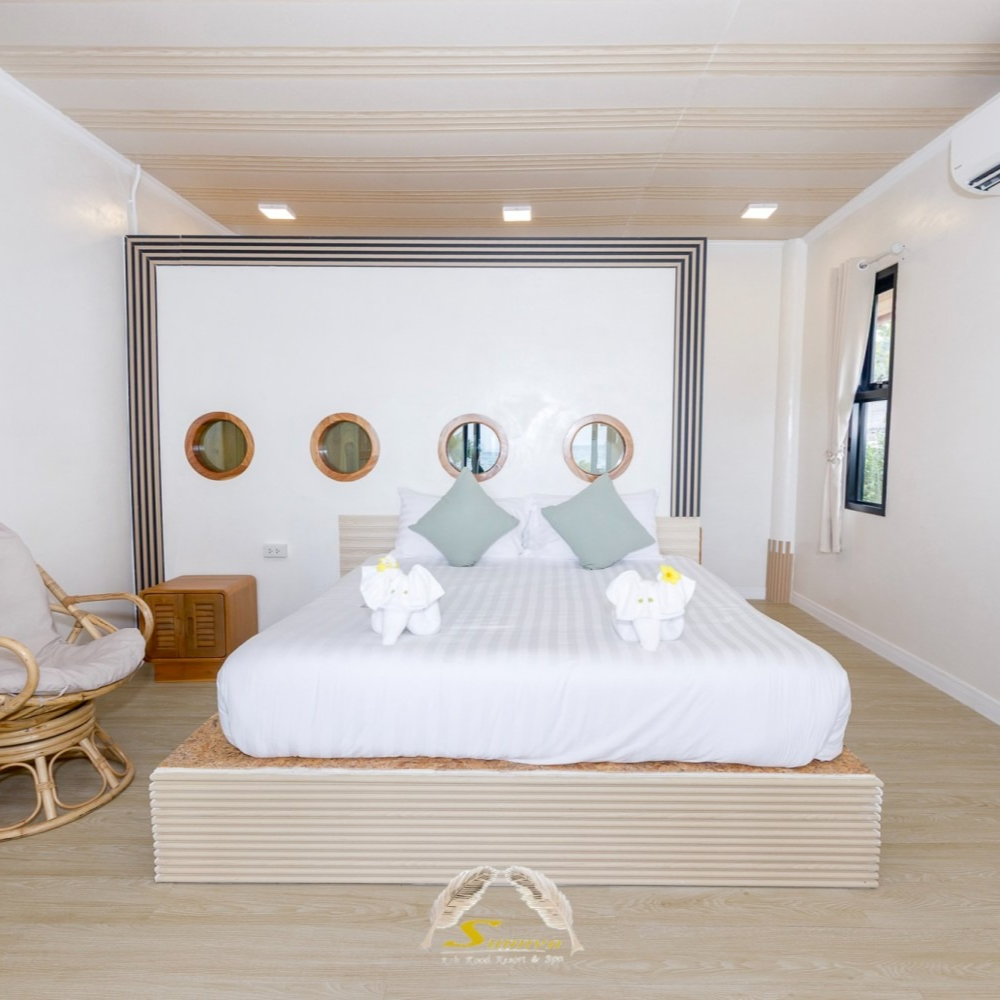 Bedroom with bed, pillows, mirrors, and rocking chair. White and wood tones create a calm, relaxing space.