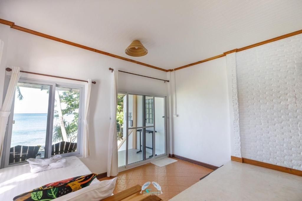 Bedroom with bed, window to sea view, balcony door, white walls, and wooden accents.