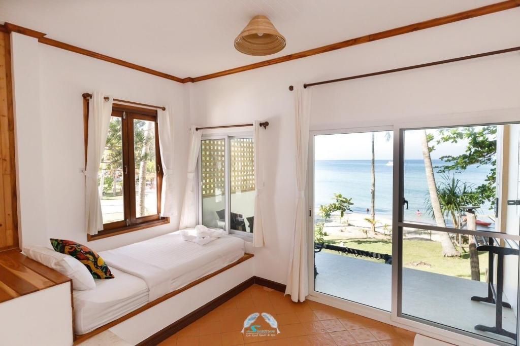 Bright hotel room with sea view, window seat, white walls, and wood trim.