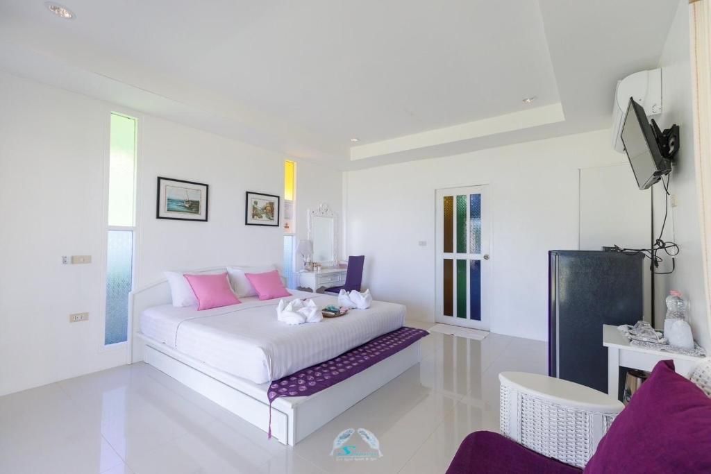 Bright, white hotel room with a bed, small sitting area, and colorful door.