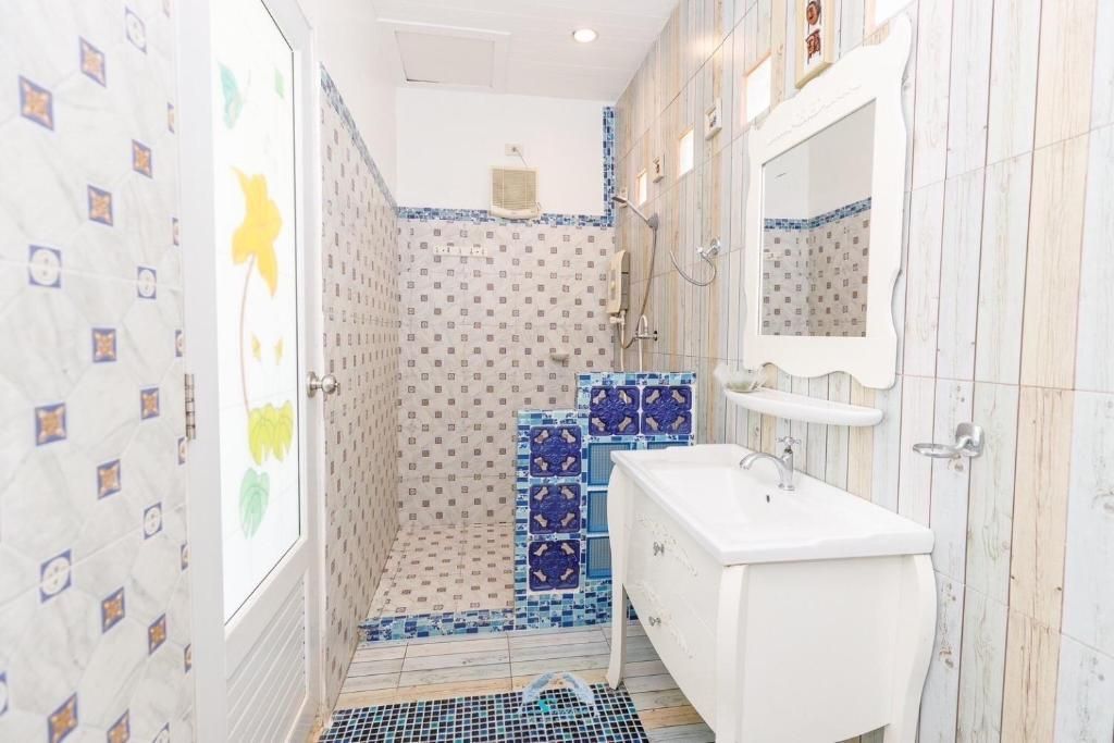 Bathroom with white sink, ornate mirror, patterned blue and white tiles, and shower.