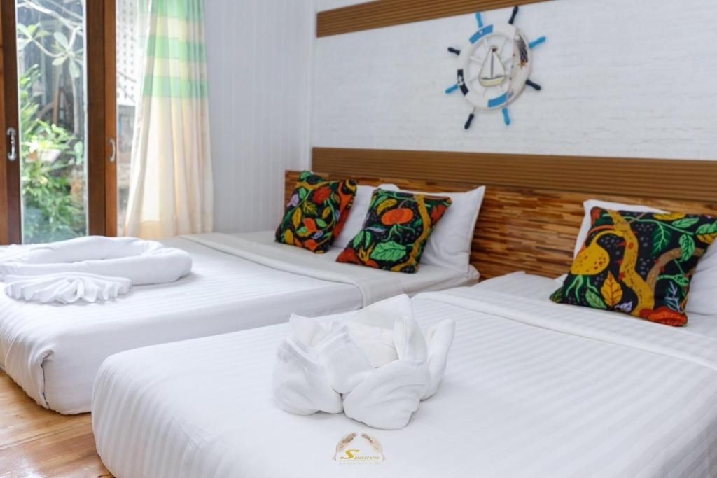 Three beds with white bedding, floral pillows, and nautical decor.