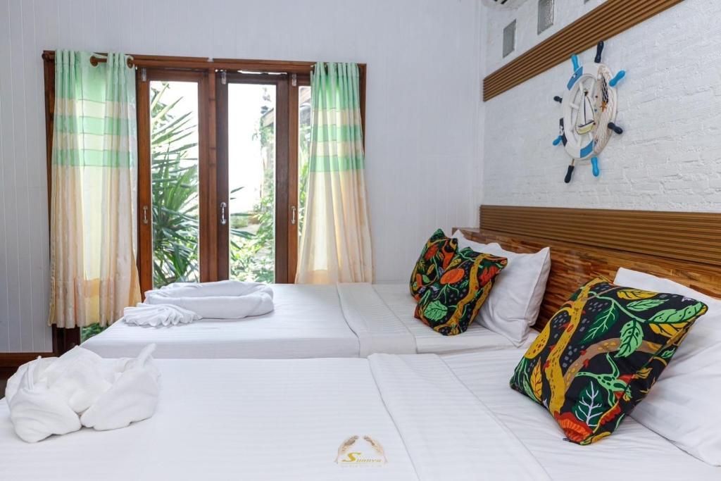 Bright bedroom with two beds, white bedding, colorful pillows, window, and nautical wall decor.