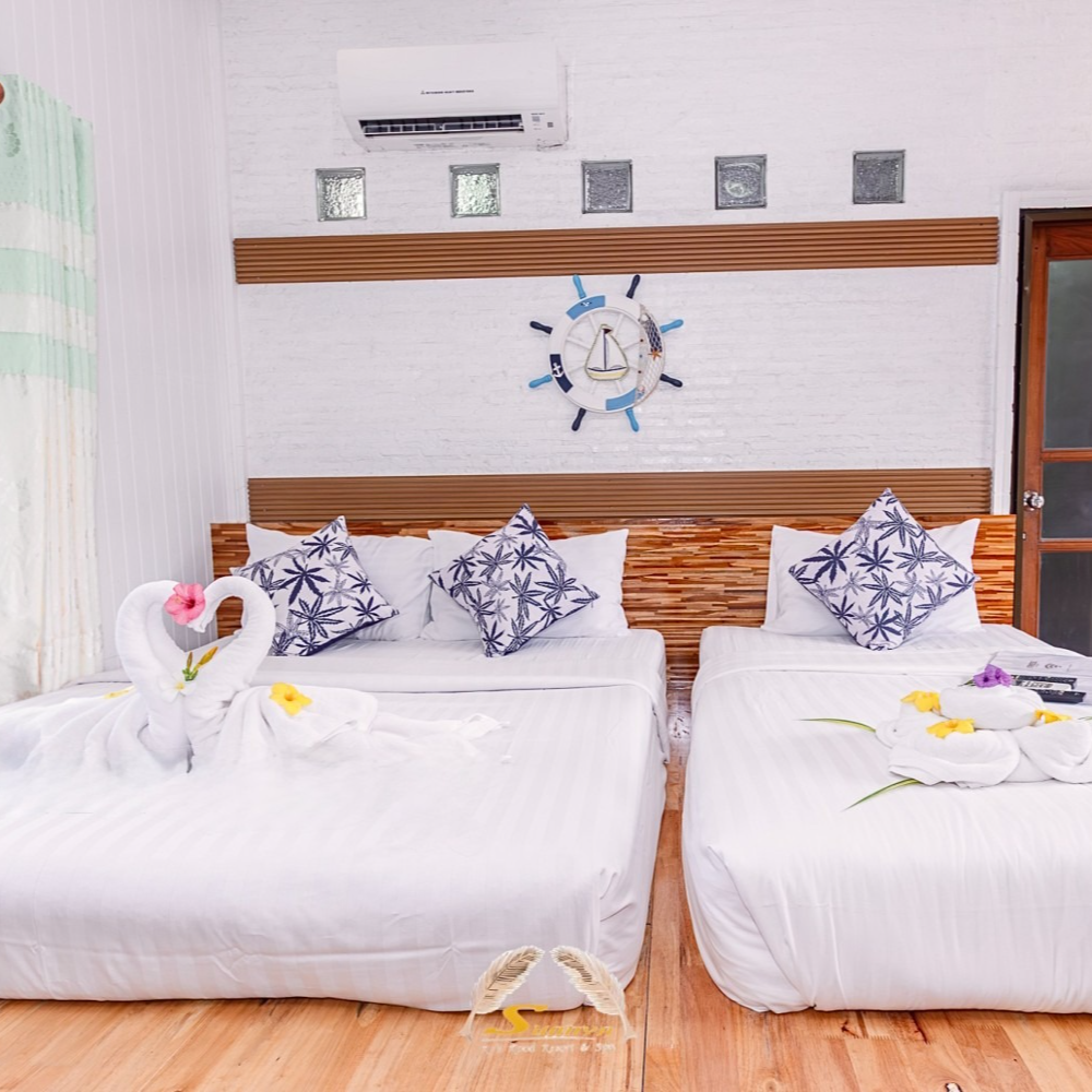 Two beds in a bright room with white linens, wooden headboards, and nautical decor.