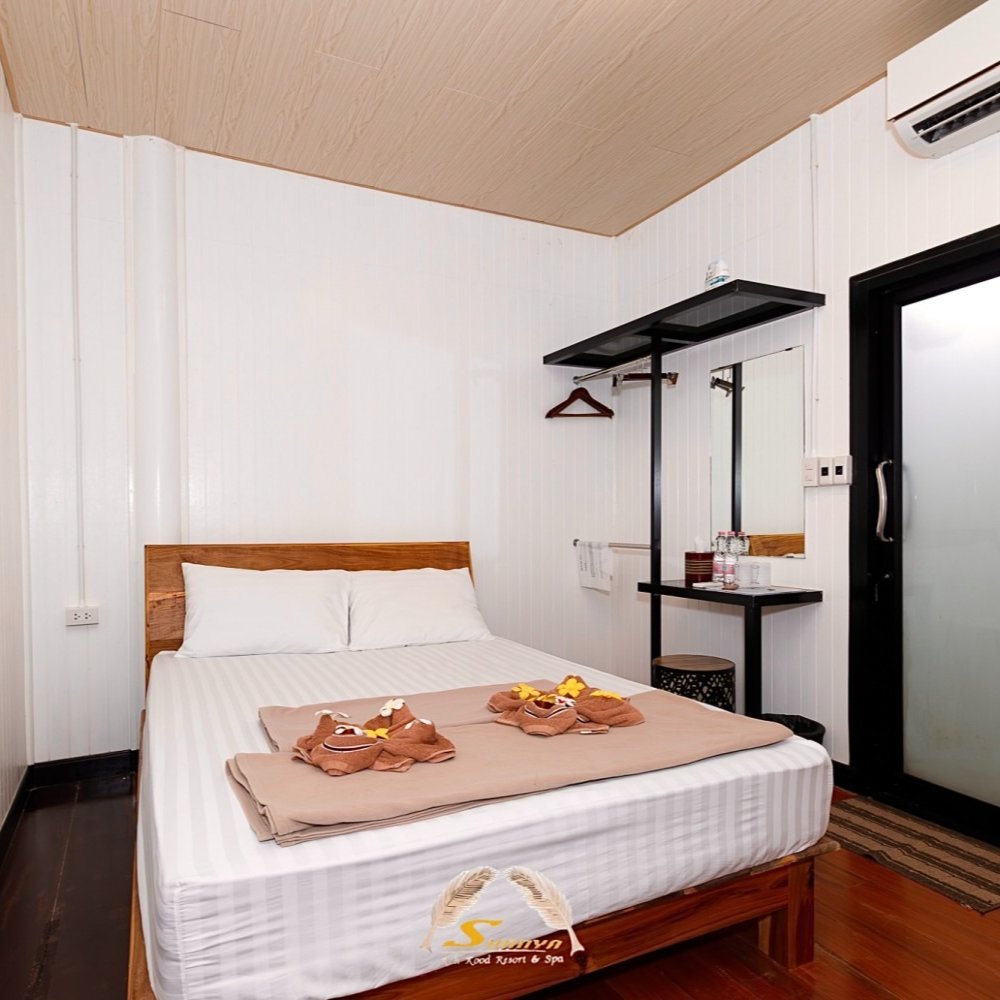 Bedroom with a wooden bed frame, white bedding, and a small table with a mirror.