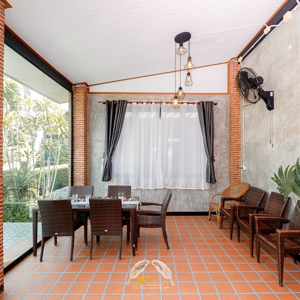 Indoor dining area with brick columns, tiled floor, glass wall, table, chairs, and fan.