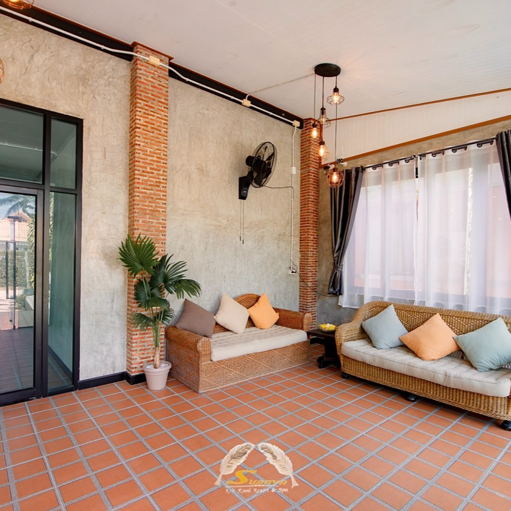 Covered patio with wicker sofas, brick columns, and a view through a glass door.