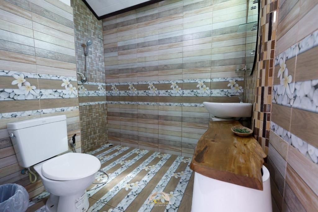 Bathroom with white toilet, wooden vanity, and tiled walls and floor.