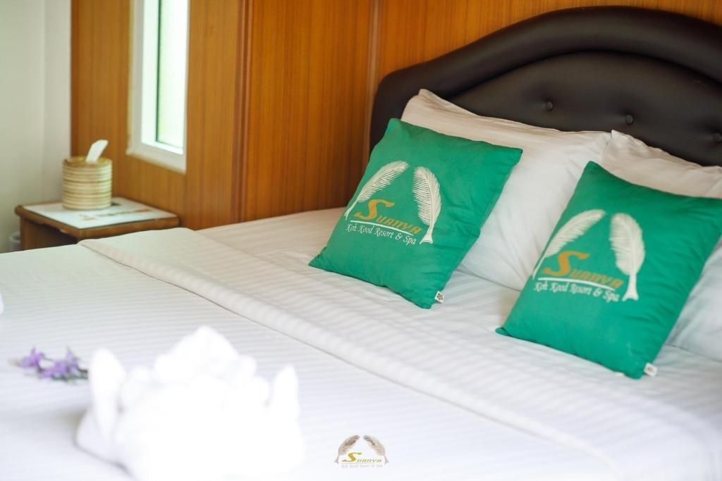 Bed with white linens, two green pillows, a nightstand, and window.