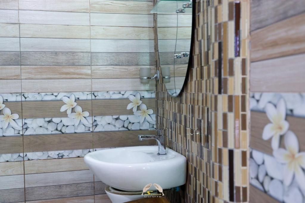 Bathroom with patterned tile, oval mirror, white sink.