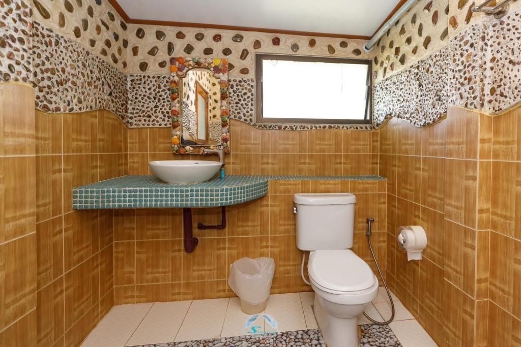 Bathroom with brown tiled walls, patterned border, and a white toilet and sink.