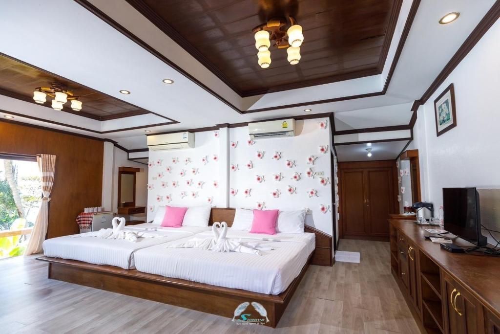Bedroom with two large beds, white bedding, pink pillows, wooden furniture, and patterned wallpaper.