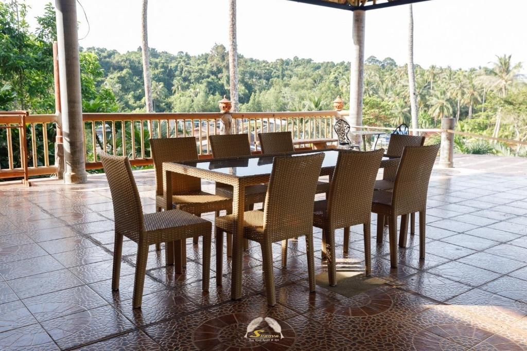 Outdoor dining area with a table and chairs, overlooking a lush, green landscape.
