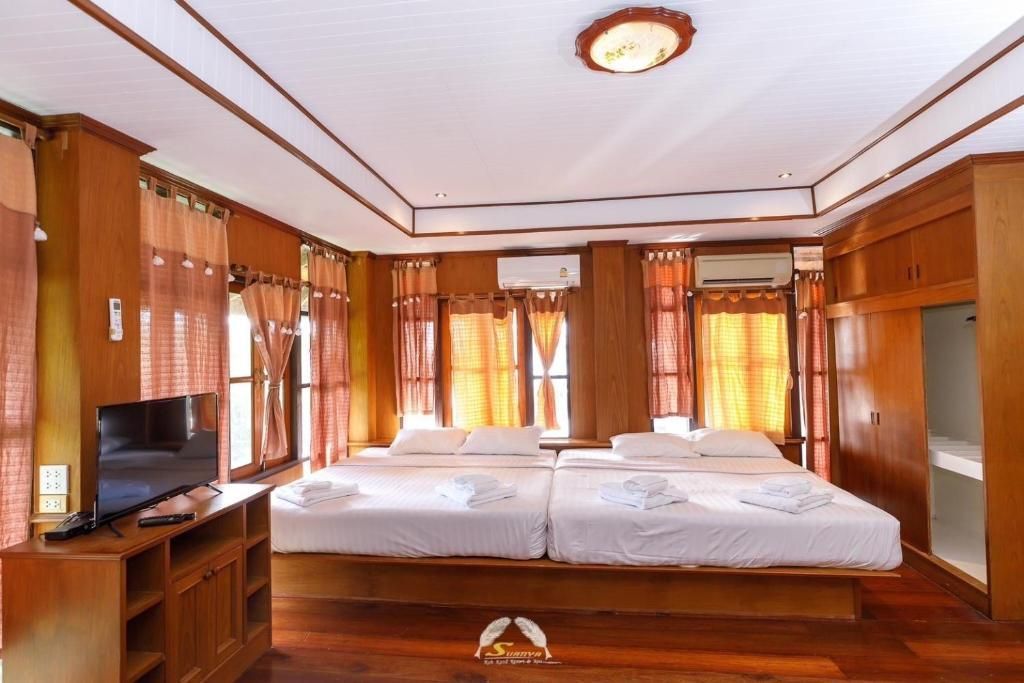 A hotel room with two beds, wooden decor, natural light, and a television.