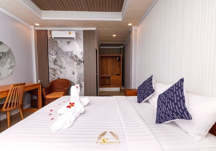 Hotel room with bed, pillows, desk, chair, and a decorative towel sculpture.