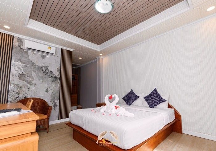 Bedroom with a bed, decorative swans, pillows, and a wooden desk.