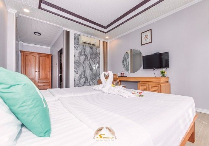 Bedroom with bed, desk, TV, and decorative swans on bed.