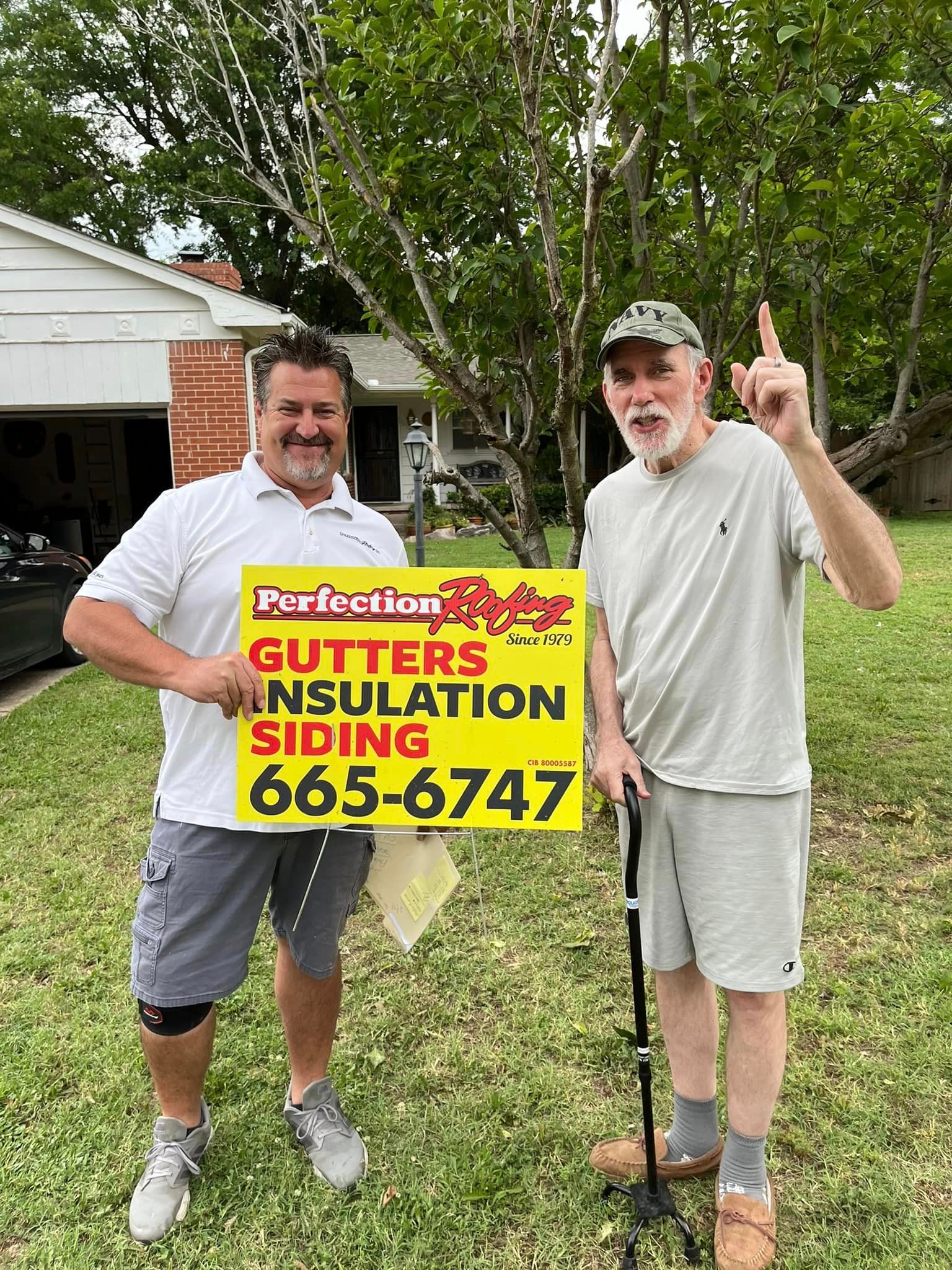 Two men are standing next to each other in front of a house holding a sign.