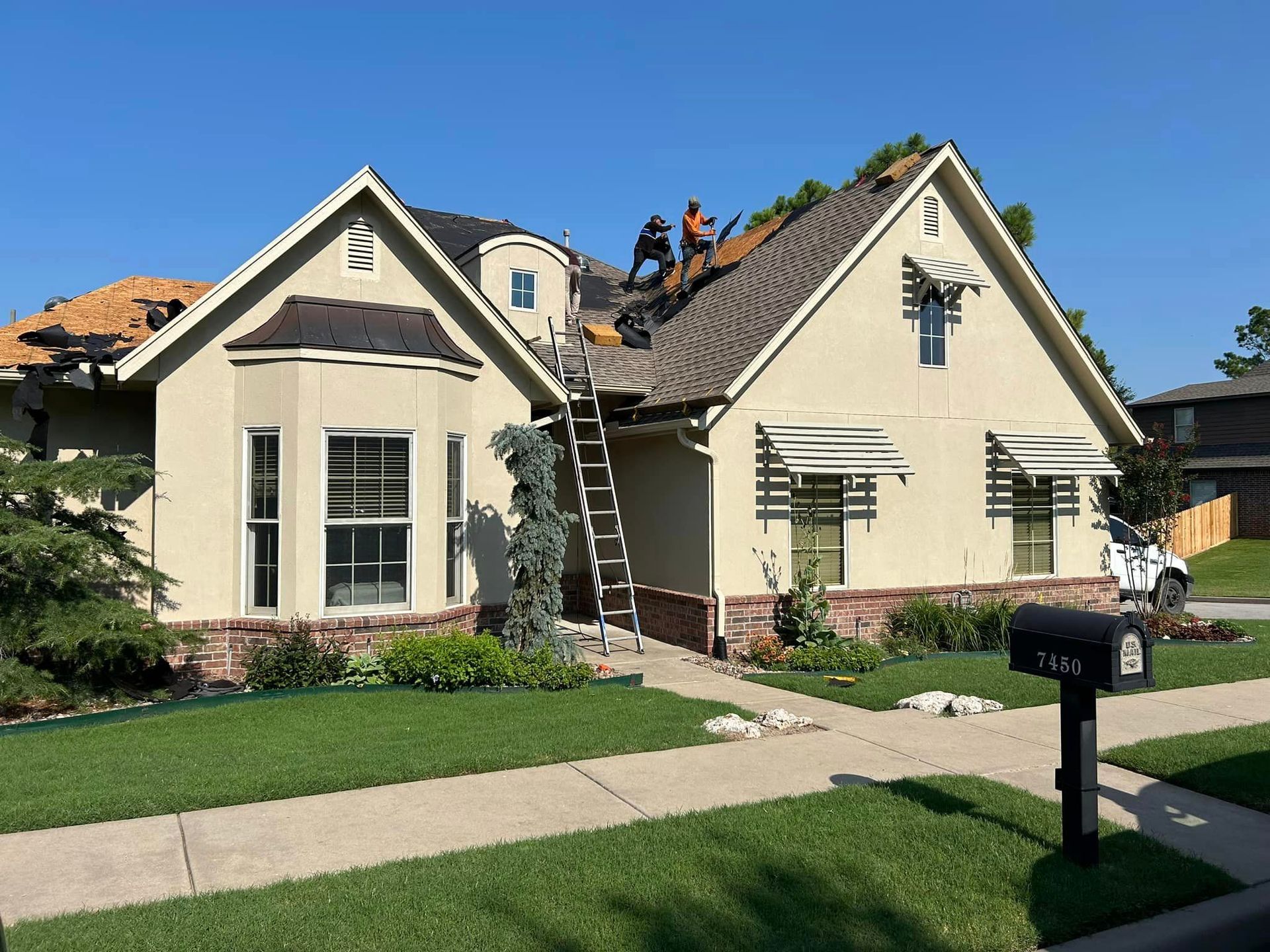 Two men are working on the roof of a house.