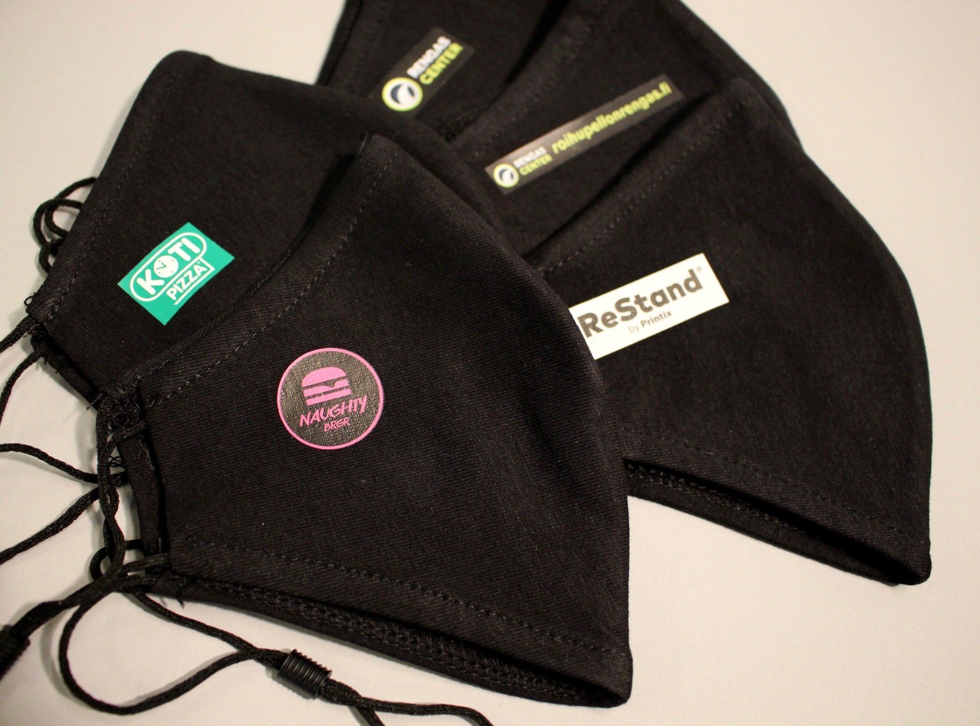 valokuva mustia kasvomaskeja joissa logotarrat