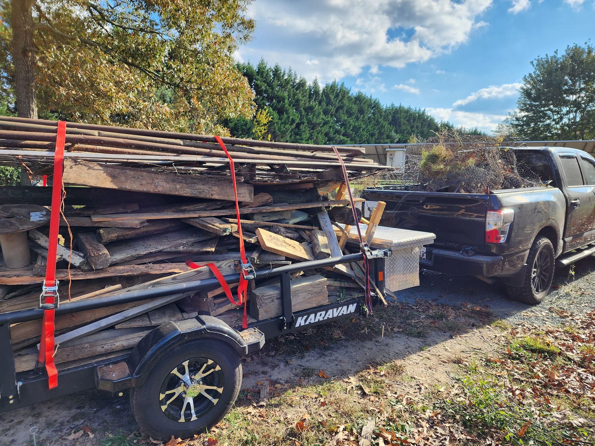 A truck is towing a trailer filled with wood.