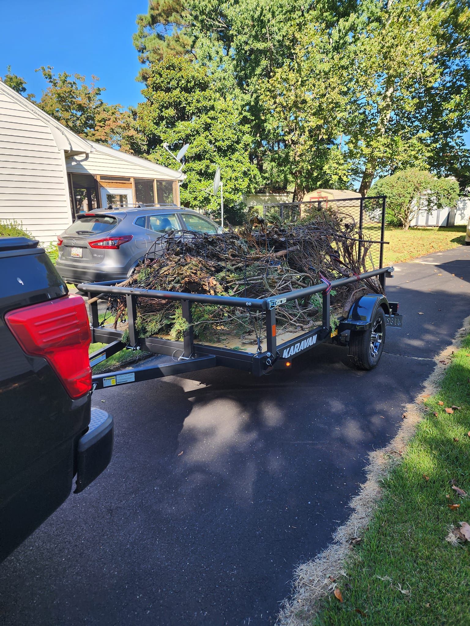 A trailer with a lot of leaves on it is parked on the side of the road.