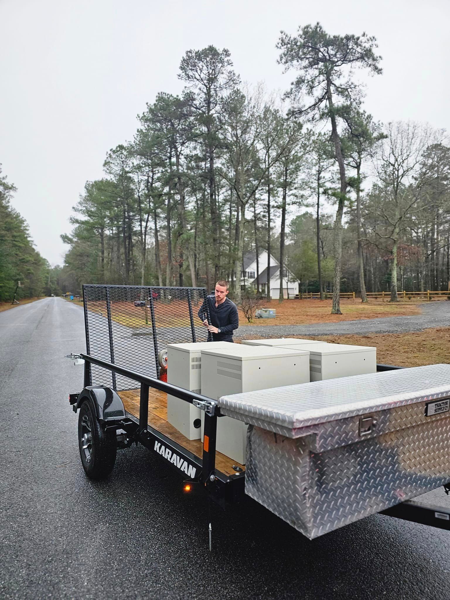 A man is standing next to a trailer with boxes on it.