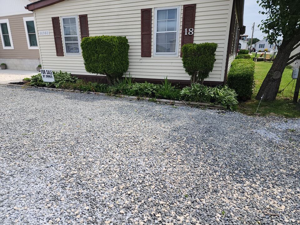A mobile home with a gravel driveway in front of it