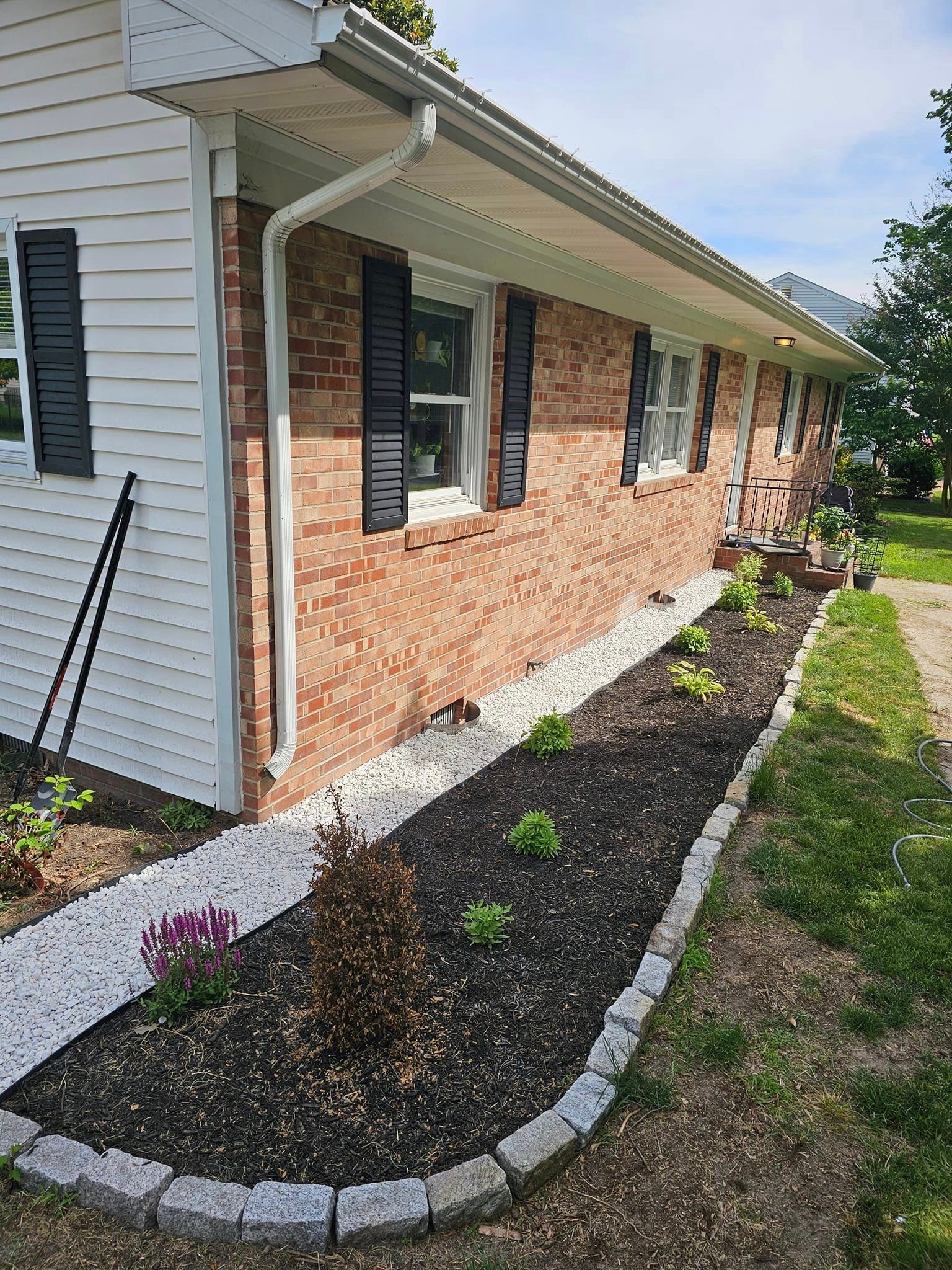 A brick house with black shutters and a walkway leading to it.