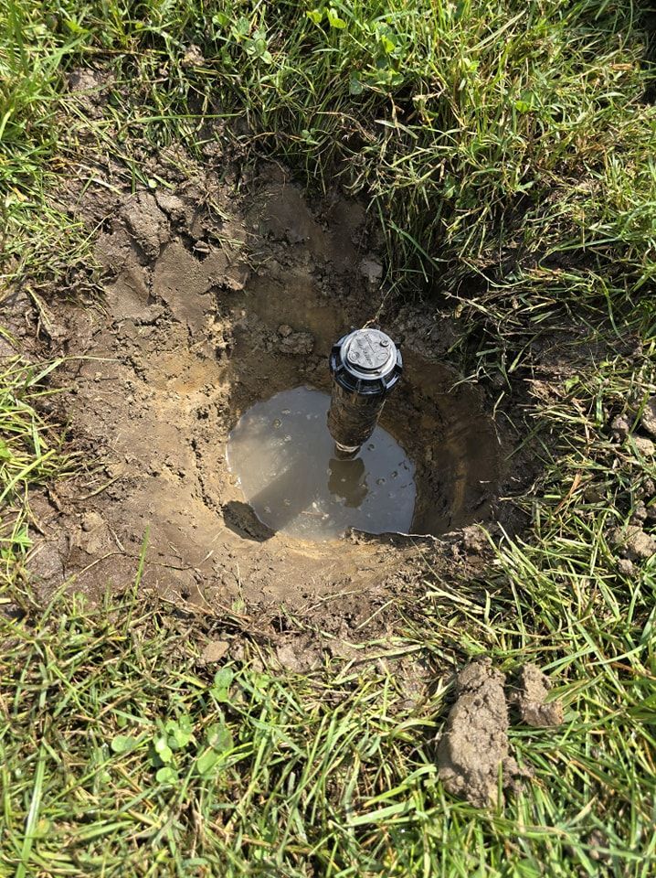 A sprinkler is sitting in the middle of a muddy hole in the ground.