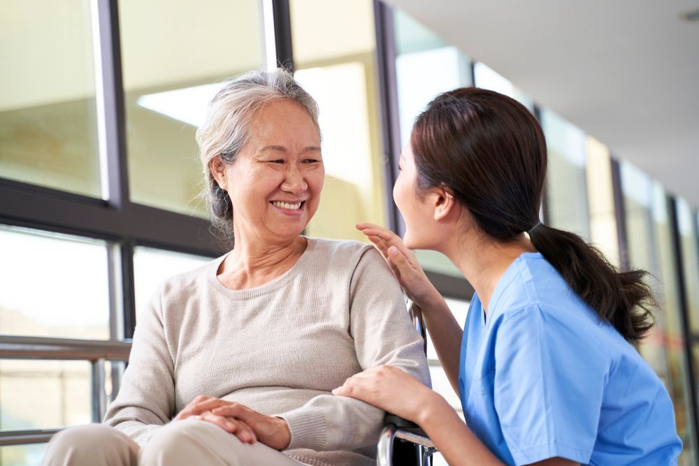 A nurse is talking to an elderly woman in a wheelchair.