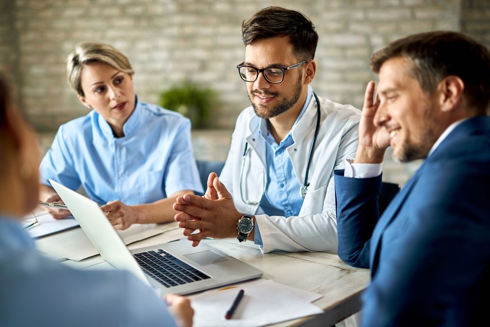 A group of doctors and business people are having a meeting at a table.