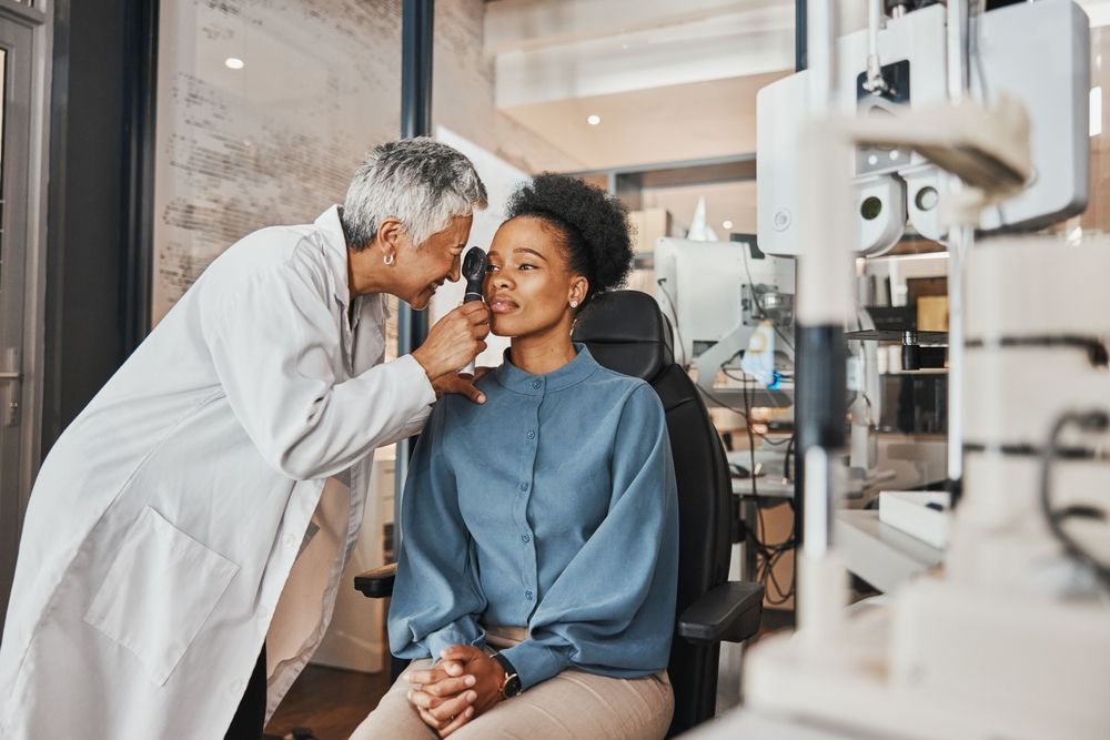 An ophthalmologist is examining a woman 's eye with a device.