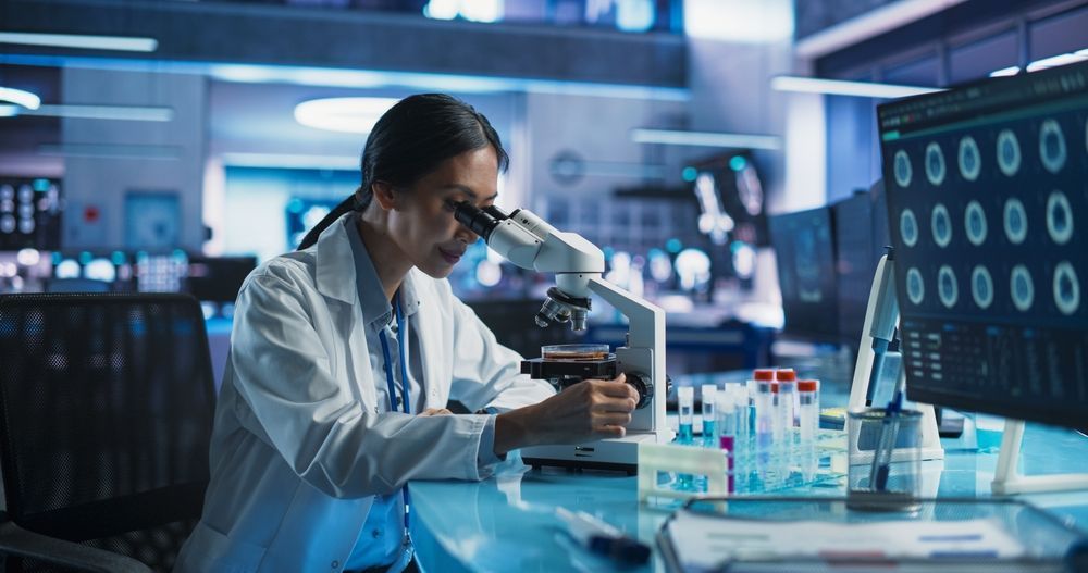 A female scientist is looking through a microscope in a laboratory.