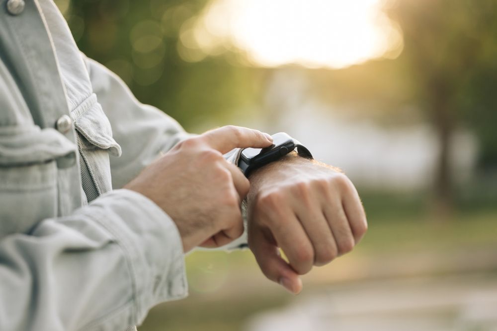 A man is looking at his smart watch on his wrist.