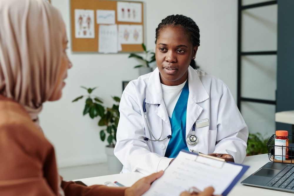 A doctor is talking to a patient while holding a clipboard.