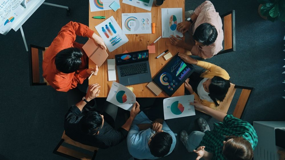 A group of people are sitting around a table looking at graphs.