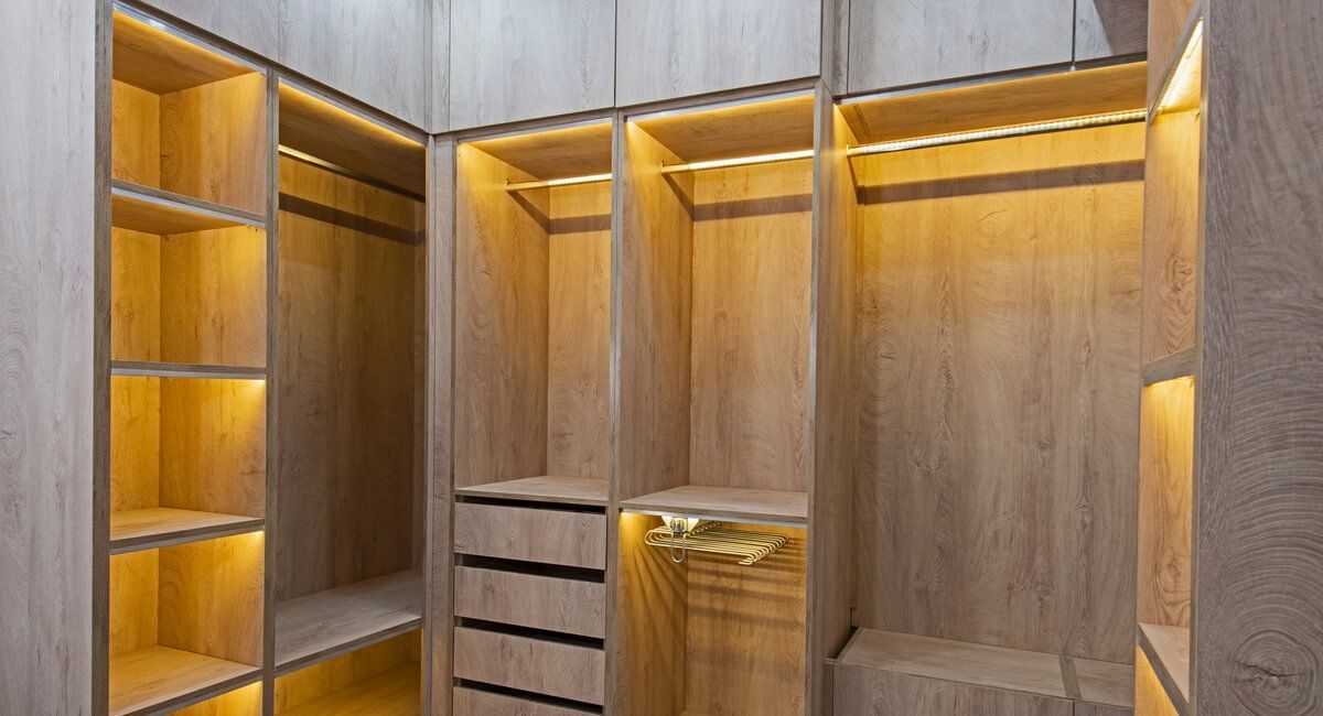 A walk in closet with lots of wooden shelves and drawers.