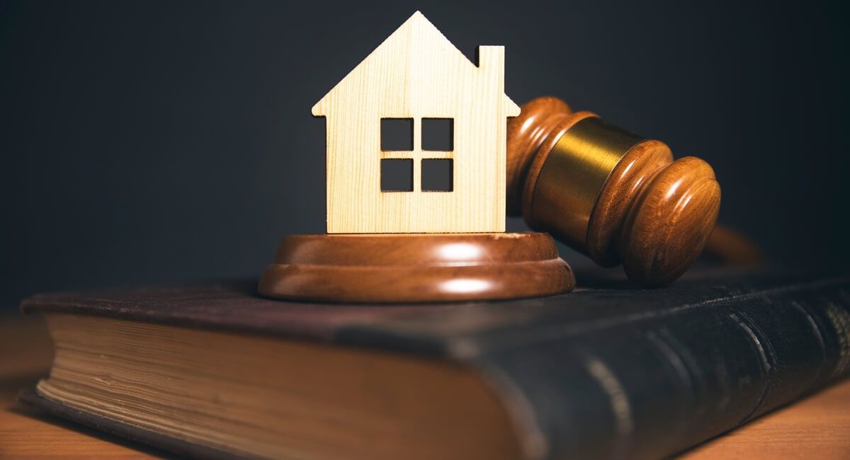 A wooden house is sitting on top of a wooden gavel on top of a book.