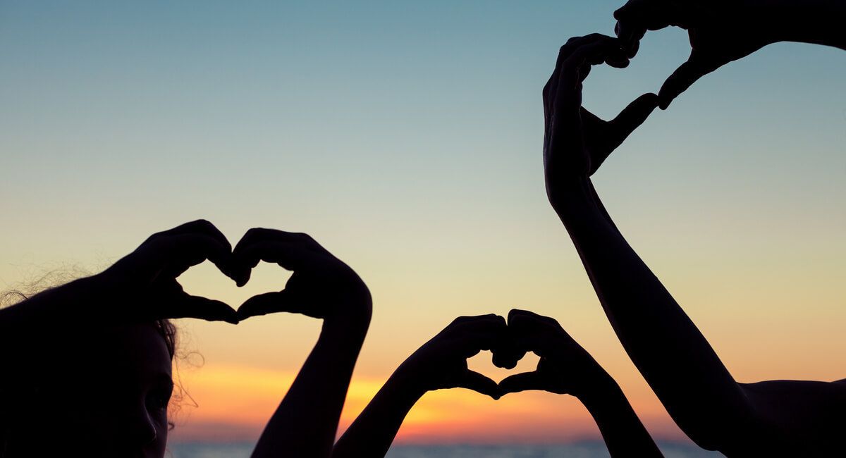 Two people are making a heart shape with their hands