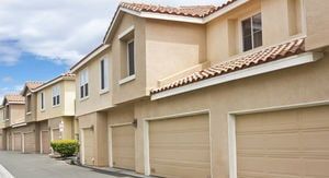 A row of apartment buildings with garage doors on a sunny day.