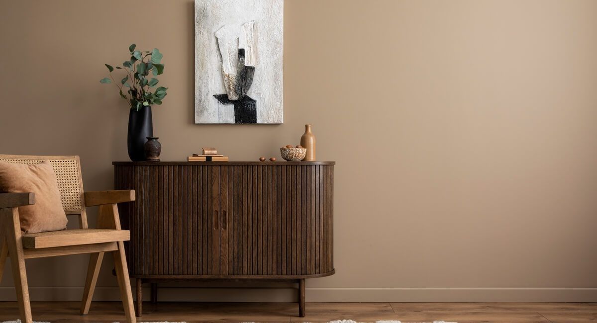 A living room with a wooden dresser , chair , table and painting on the wall.