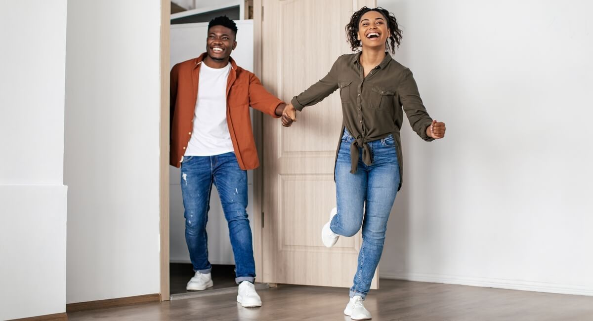 A man and a woman are holding hands and jumping in a room.