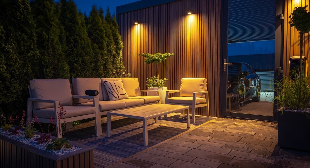 A patio with a couch , chairs and a table at night.